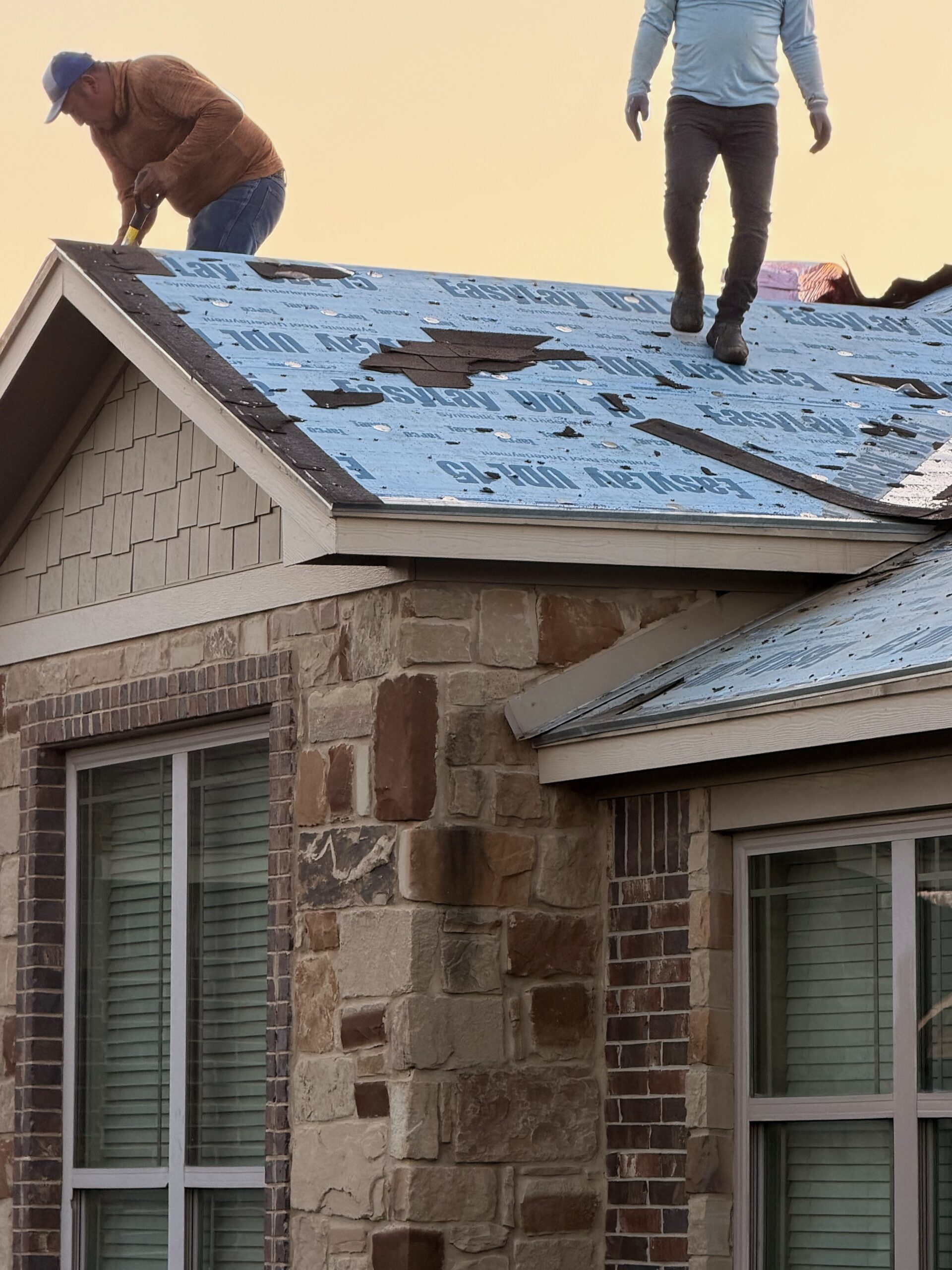 Roofing crew completing tear-off and dry-in during a roof replacement in Temple, TX